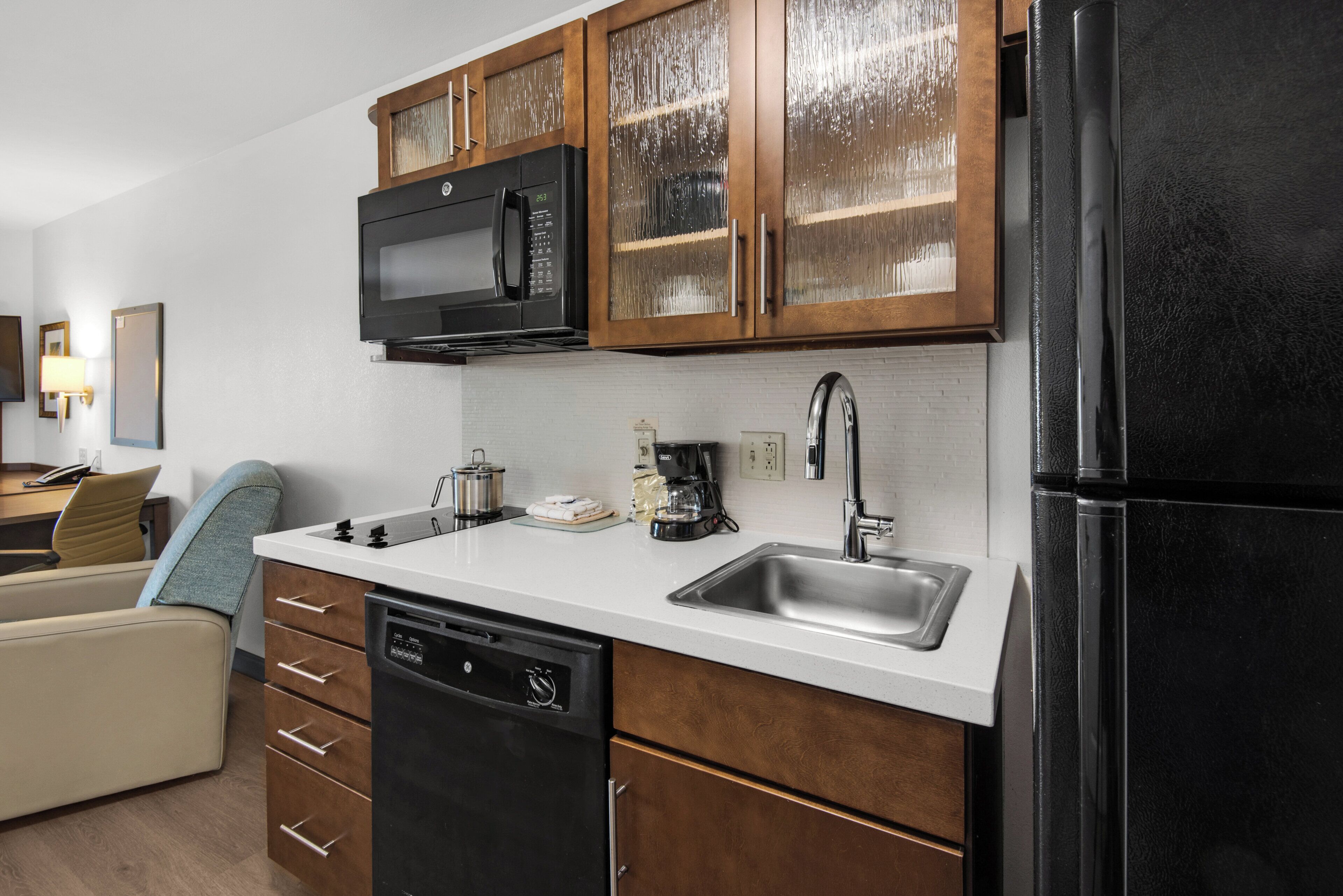 A modern kitchen with wooden cabinets, a black refrigerator, a microwave, and a dishwasher.