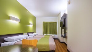 A hotel room with two beds, a wooden table, a green and beige bedspread, a window with green curtains, and a mounted TV. - Days Inn by Wyndham South Bend / Notre Dame (South Bend)