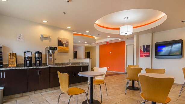 A modern cafe with a coffee machine, a menu board, and a TV screen. - Days Inn by Wyndham South Bend / Notre Dame (South Bend)
