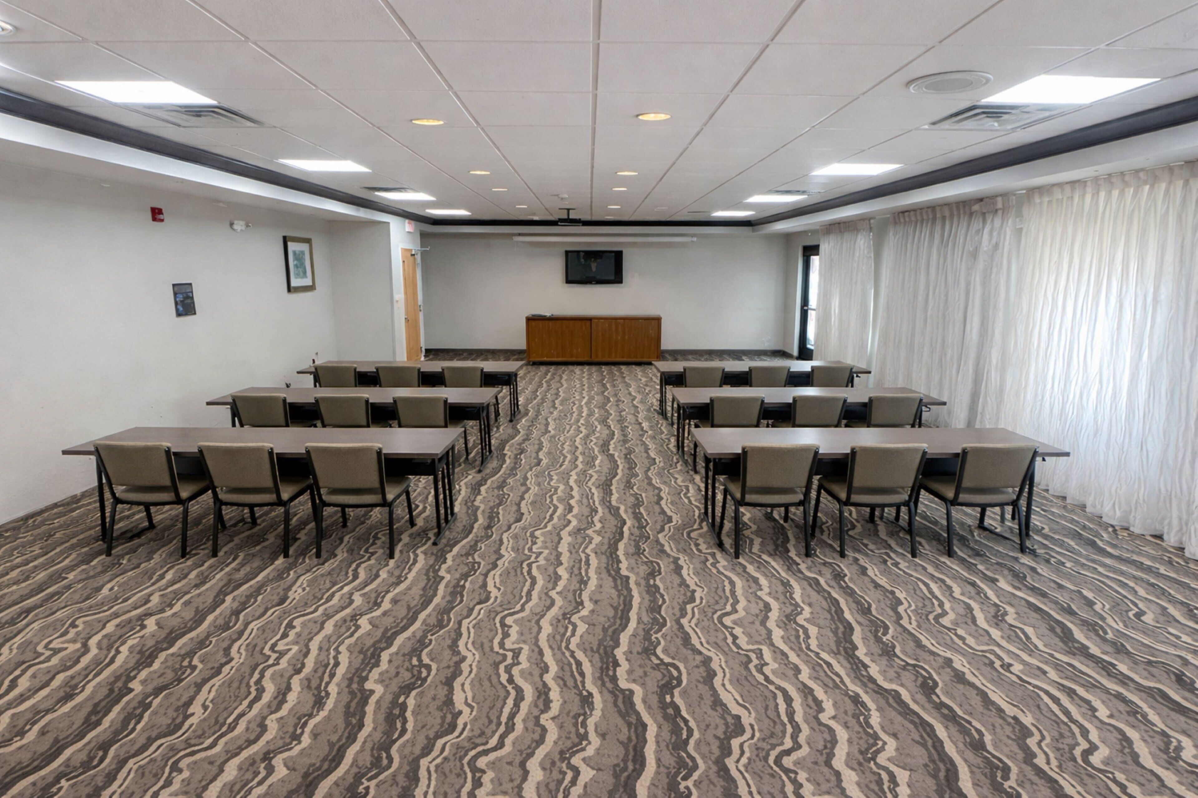 A conference room with a patterned carpet, multiple tables, and chairs arranged for meetings.