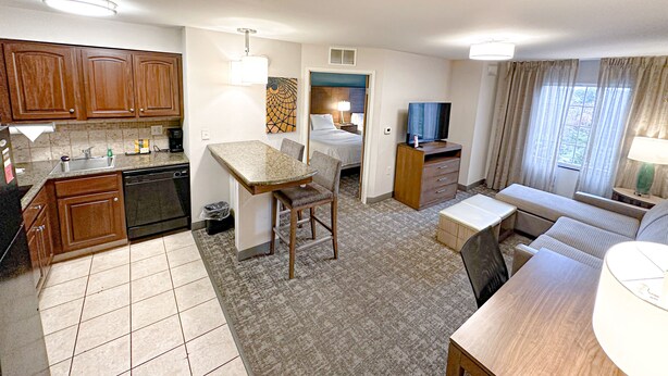 A compact hotel room with a kitchenette, a dining area, a seating area, and a television. - Staybridge Suites Elkhart North by IHG (Elkhart)