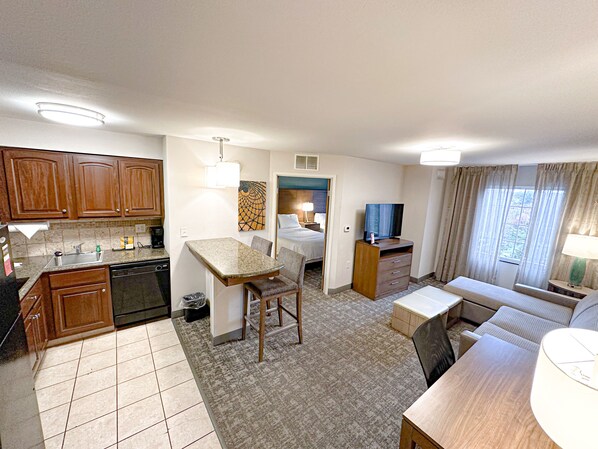 A compact hotel room with a kitchenette, a dining area, a seating area, and a television. - Staybridge Suites Elkhart North by IHG (Elkhart)