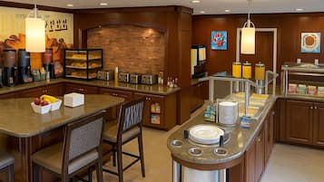 Una cocina de hotel con una isla central, barra de desayuno y varios electrodomésticos.