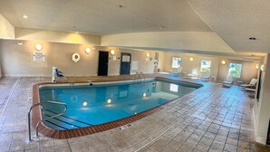 An indoor swimming pool with a lifeguard chair, poolside chairs, and a sign warning of no lifeguard on duty. - Staybridge Suites Elkhart North by IHG (Elkhart)
