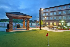 A hotel with a covered outdoor seating area, a pool, and a well-maintained lawn. - Staybridge Suites Elkhart North by IHG (Elkhart)
