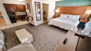 A hotel room with a bed, bedside tables, a desk, a chair, a small kitchenette, and a bathroom. - Staybridge Suites Elkhart North by IHG (Elkhart)