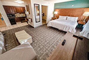 A hotel room with a bed, bedside tables, a desk, a chair, a small kitchenette, and a bathroom. - Staybridge Suites Elkhart North by IHG (Elkhart)