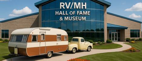 Edificio del Salón de la Fama y Museo de vehículos recreativos, con una autocaravana y un camión antiguos estacionados al frente.