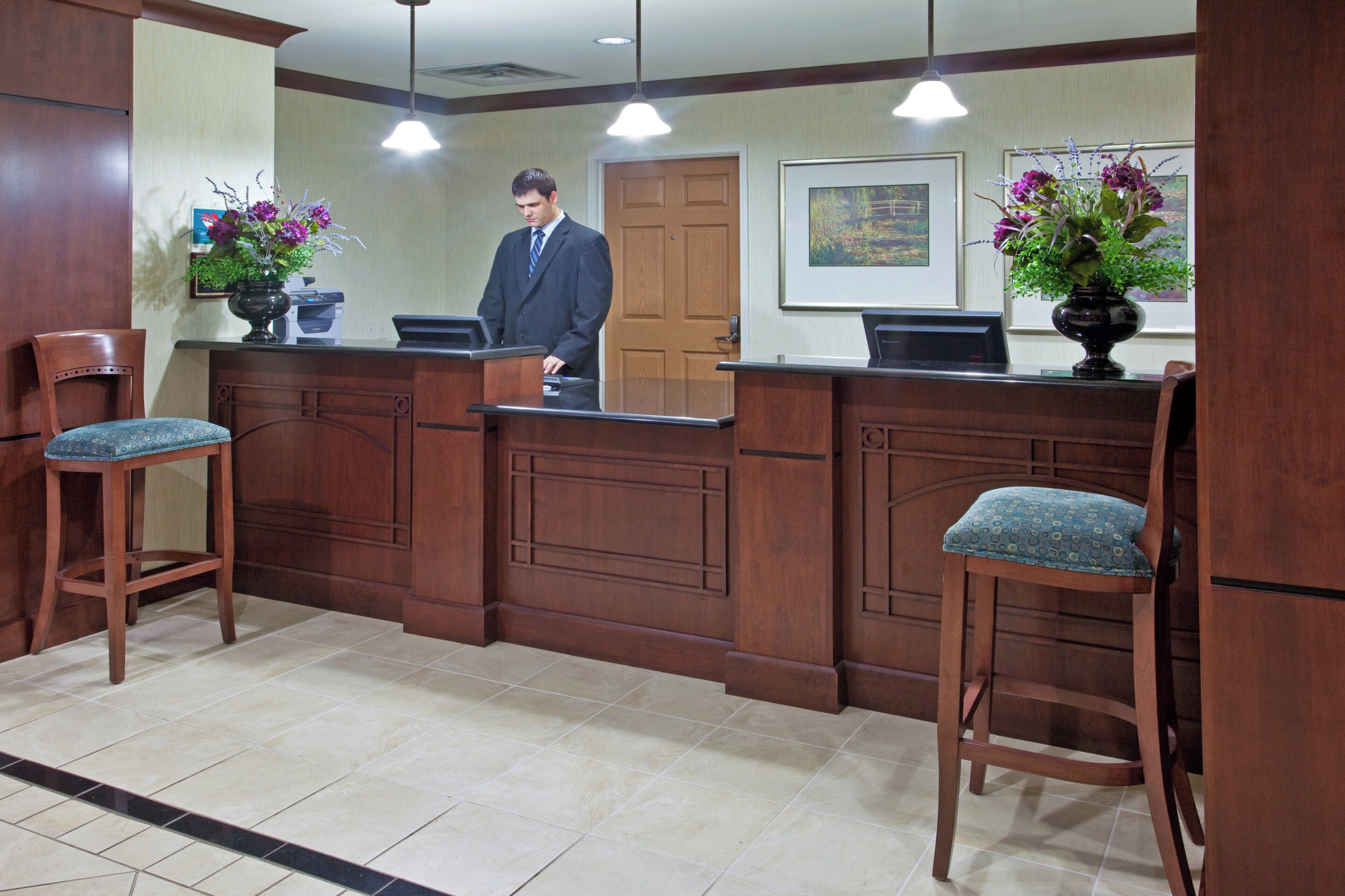 A reception area with a wooden counter, two barstools, and a door in the background.