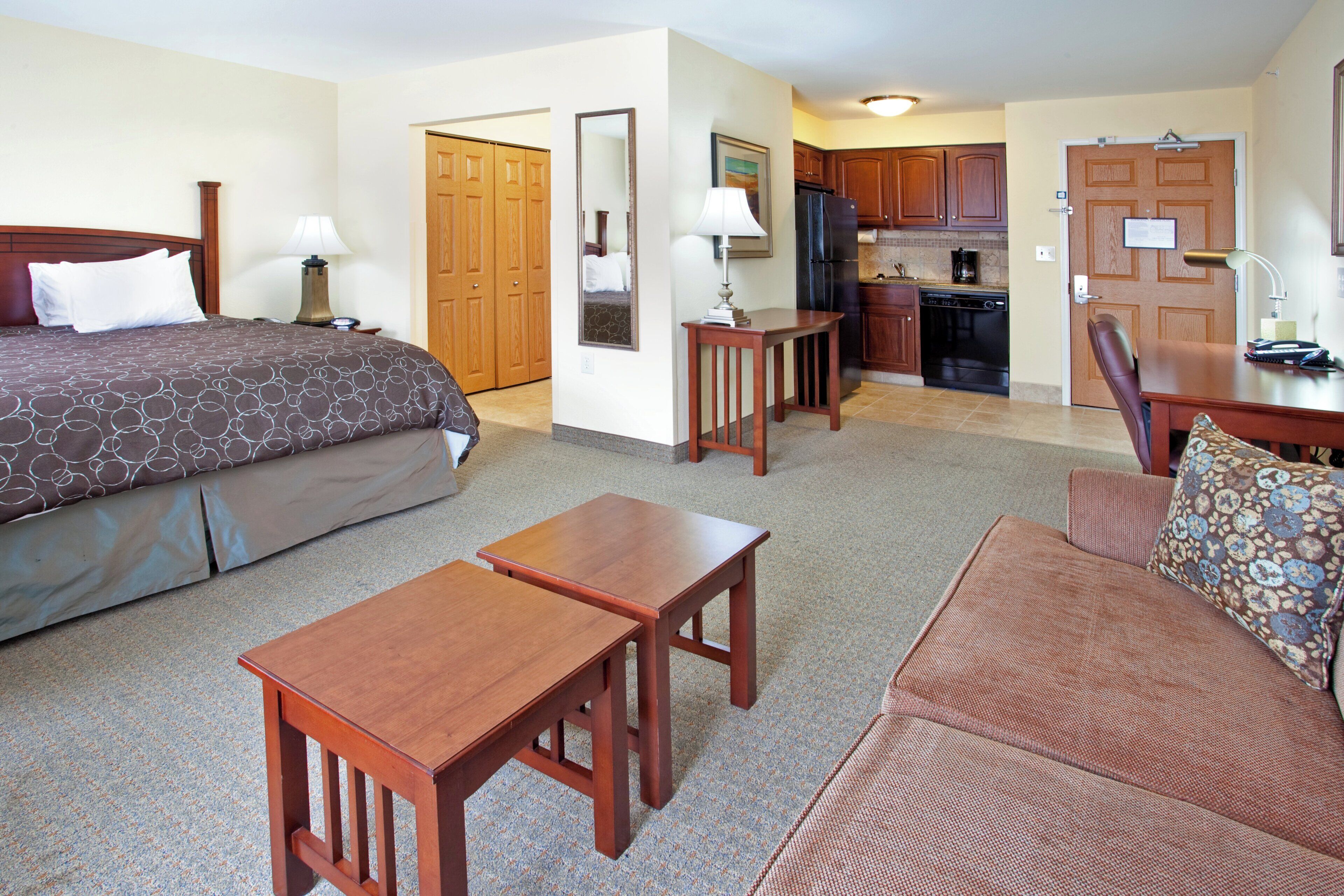 Habitación de hotel con cama, sofá, escritorio, silla, zona de cocina y baño.