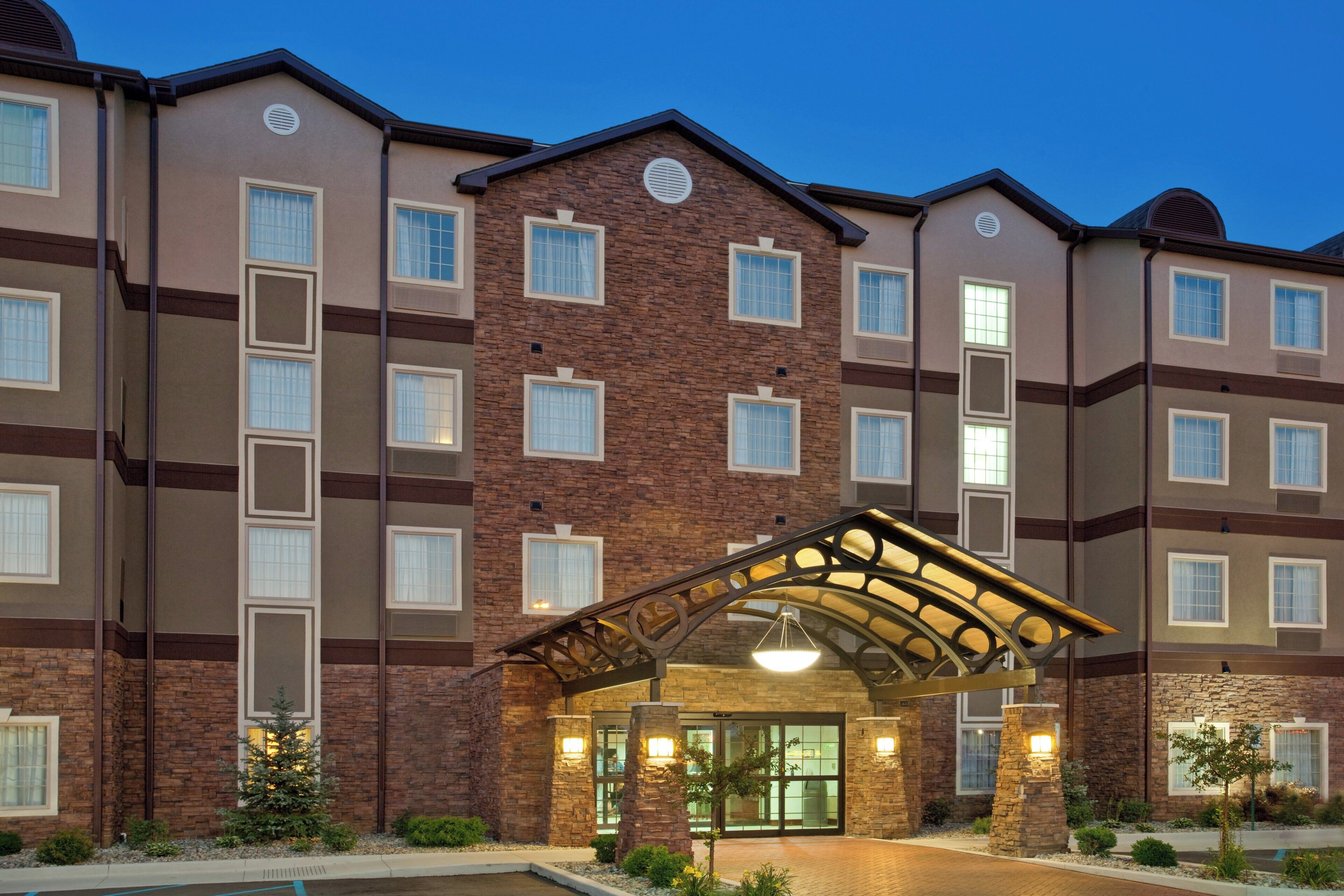 A multi-story hotel with a brick facade, large windows, and a covered entrance.