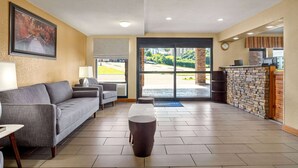 A reception area with a sofa, a coffee table, a reception desk, and a view of the outside. - Howard Johnson by Wyndham Pigeon Forge (Pigeon Forge)
