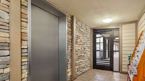 A hallway with a stone wall, a closed elevator door, and a wooden bookshelf. - Howard Johnson by Wyndham Pigeon Forge (Pigeon Forge)