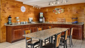 A kitchen with wooden paneling, granite countertops, and a breakfast bar with seating. - Howard Johnson by Wyndham Pigeon Forge (Pigeon Forge)