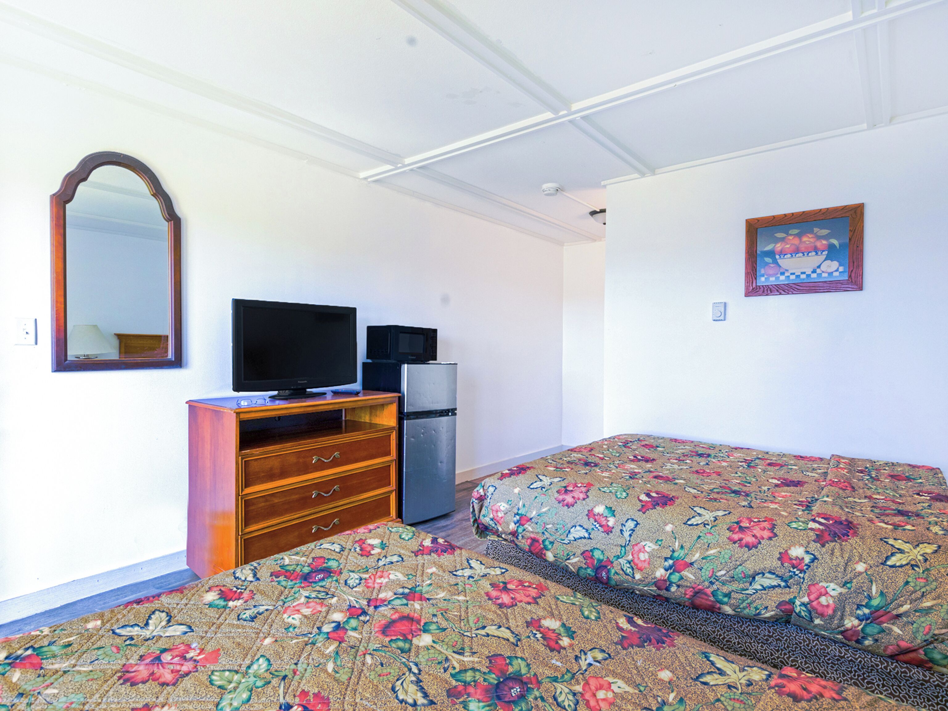 A room with a bed, a dresser, a television, and a refrigerator.