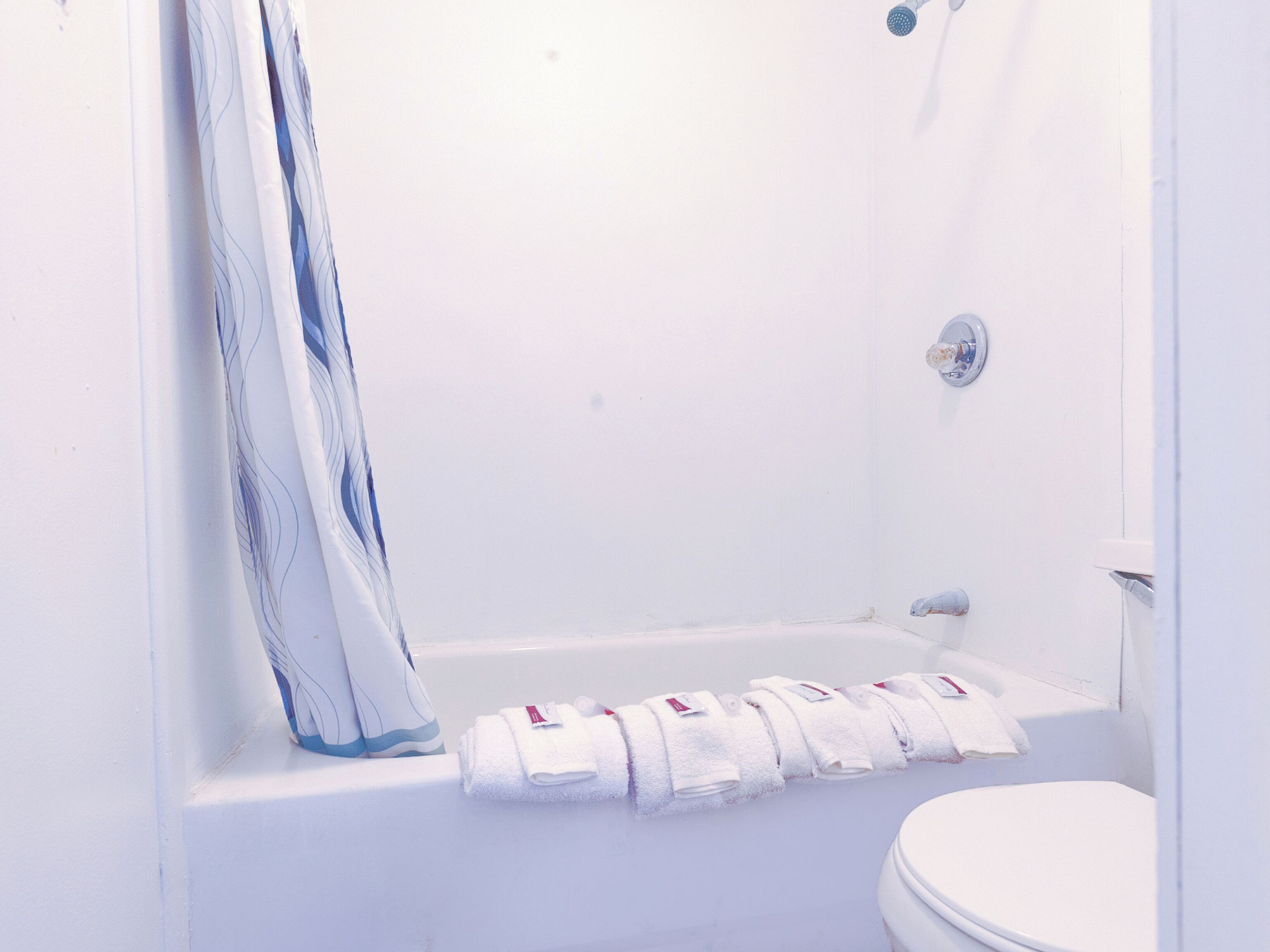 Une salle de bain blanche avec une baignoire, un rideau de douche et des toilettes.