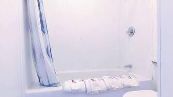 Une salle de bain blanche avec une baignoire, un rideau de douche et des toilettes.