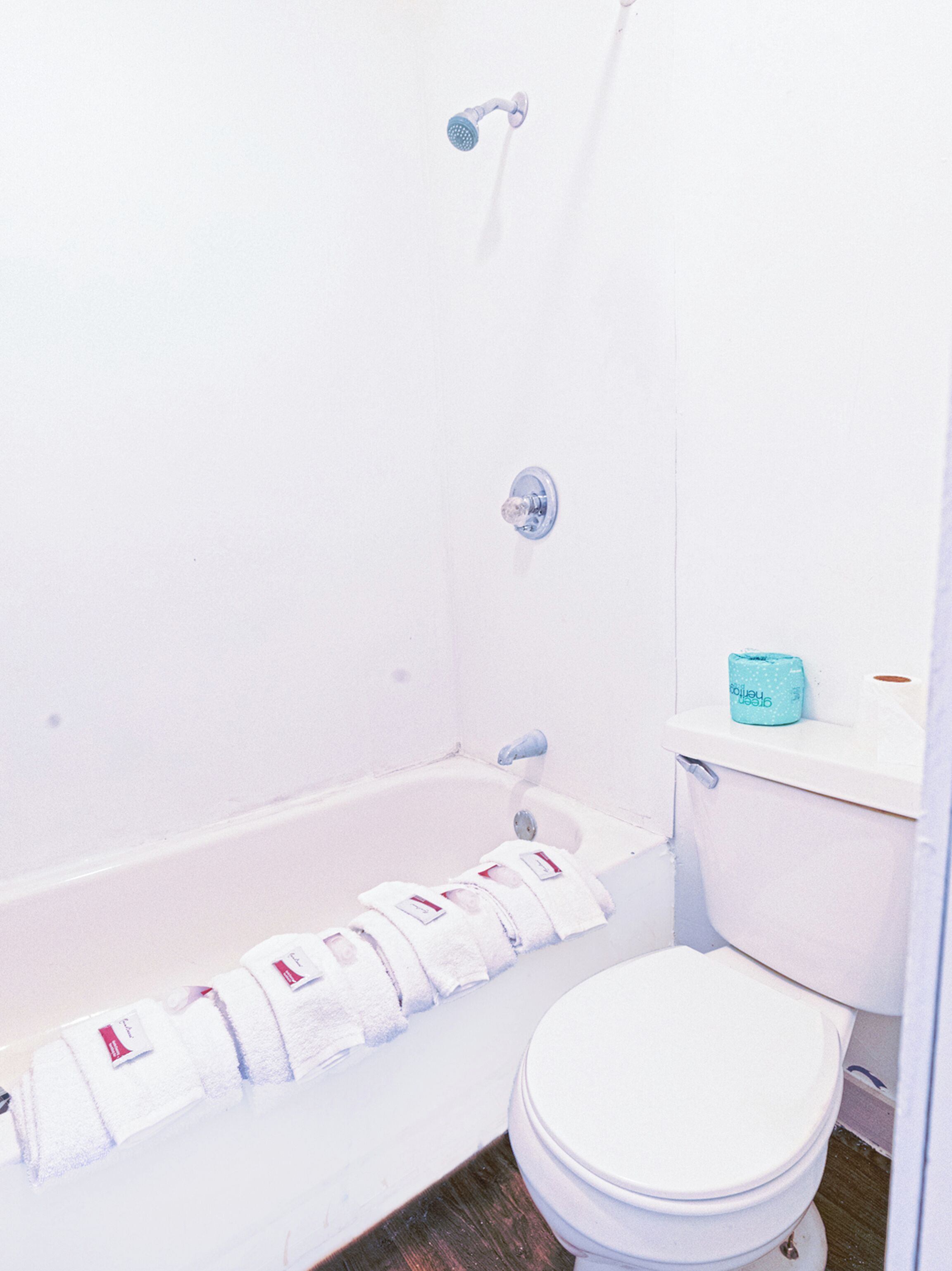 A bathroom with a bathtub, toilet, and a towel rack with towels.