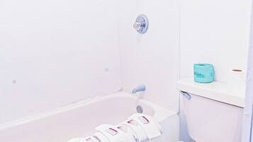 A bathroom with a bathtub, toilet, and a towel rack with towels.