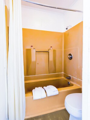 A bathroom with a bathtub, a toilet, and a shower curtain. - Country Hearth Inn & Suites By OYO Sturgis (Sturgis)