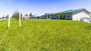 A building with a green roof, a grassy lawn, and a clear blue sky. - Country Hearth Inn & Suites By OYO Sturgis (Sturgis)