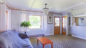A hotel lobby with a patterned carpet, a sofa, a small table, a chandelier, and a reception desk with a phone and a poster. - Country Hearth Inn & Suites By OYO Sturgis (Sturgis)