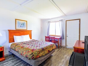 A hotel room with a bed, a desk, a chair, a television, and a door. - Country Hearth Inn & Suites By OYO Sturgis (Sturgis)
