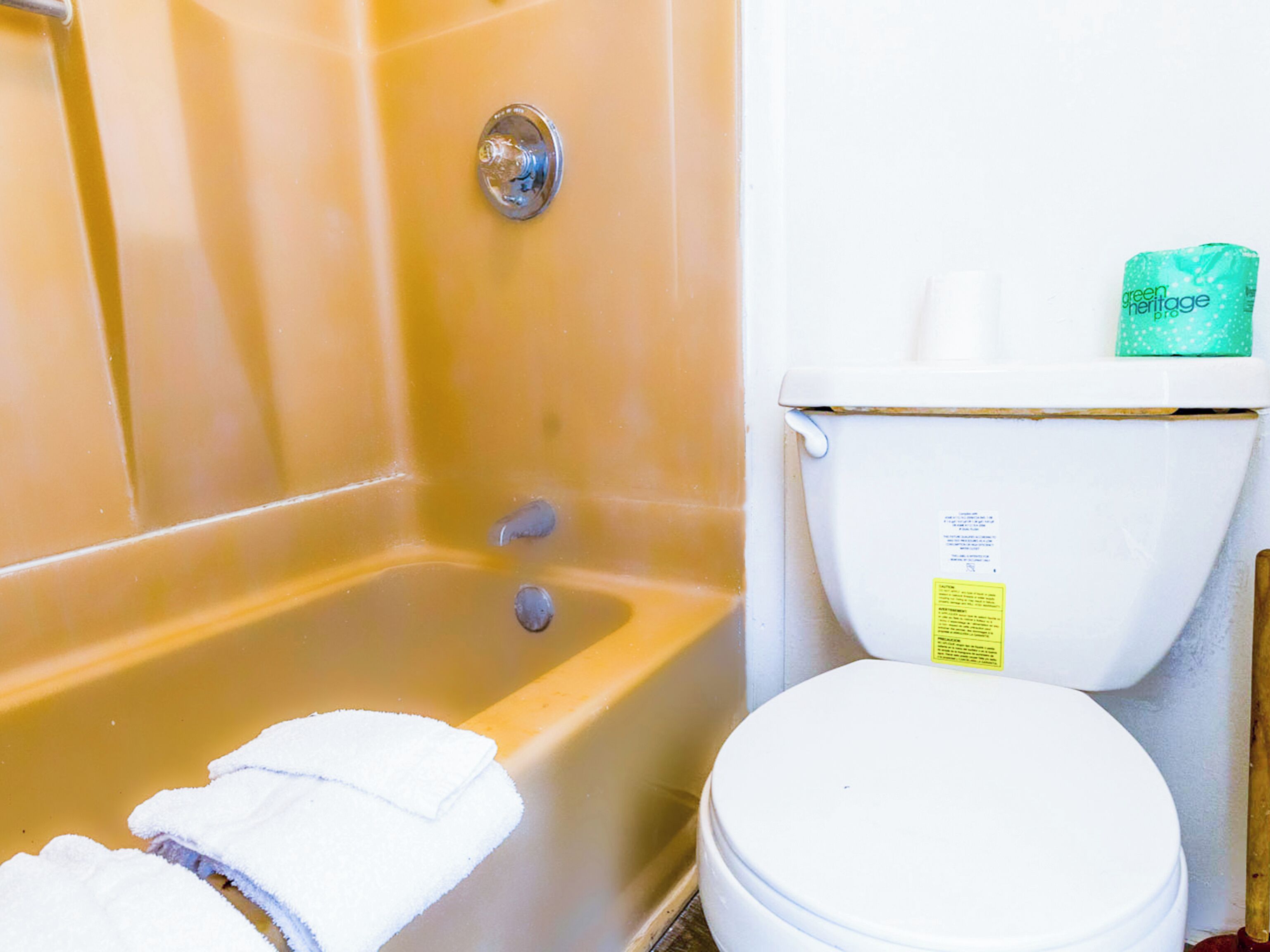 A bathroom with a bathtub, toilet, and a green package on the toilet tank.