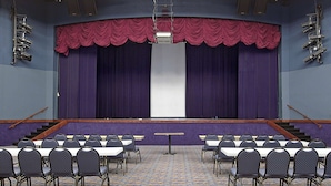 A conference room with a stage, chairs, and a carpeted floor. - Baymont by Wyndham Metropolis (Metropolis)