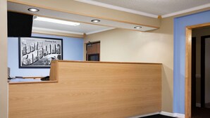 A reception area with a wooden reception desk, a framed welcome sign, and a black mat with a logo. - Super 8 by Wyndham Charlotte University (Charlotte)