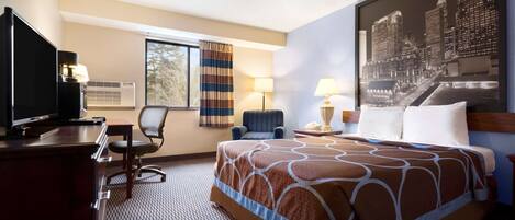 A hotel room with a bed, a desk, a chair, a television, and a window with curtains.