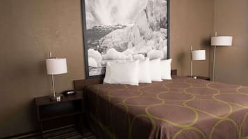 A hotel room with a large bed, two bedside lamps, a nightstand with a lamp, and a framed photograph on the wall.