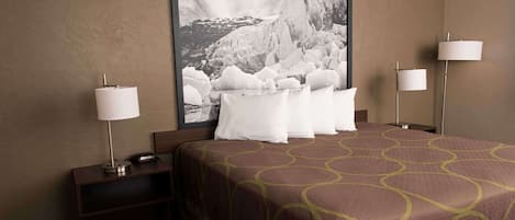 A hotel room with a large bed, two bedside lamps, a nightstand with a lamp, and a framed photograph on the wall.