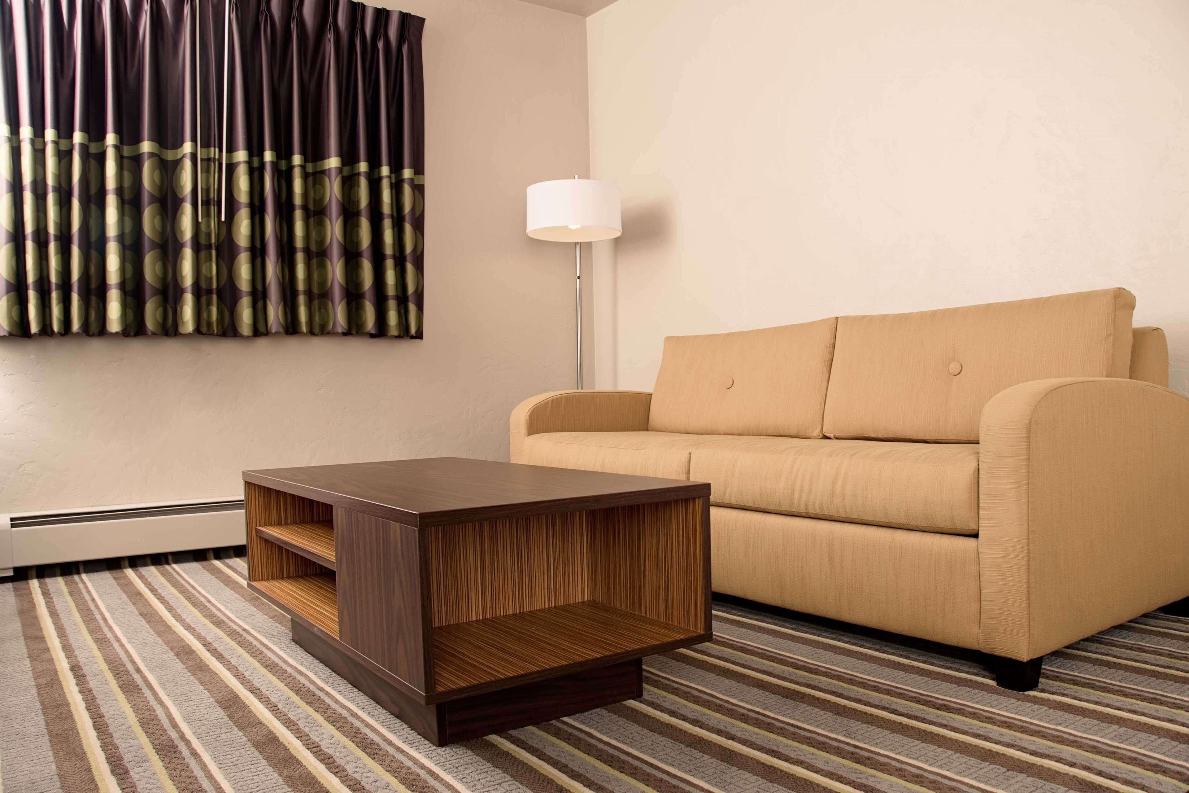 A modern living room with a sofa, a wooden coffee table, a floor lamp, and a patterned rug.