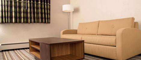 Una sala de estar moderna con un sofá, una mesa de centro de madera, una lámpara de pie y un tapete estampado.