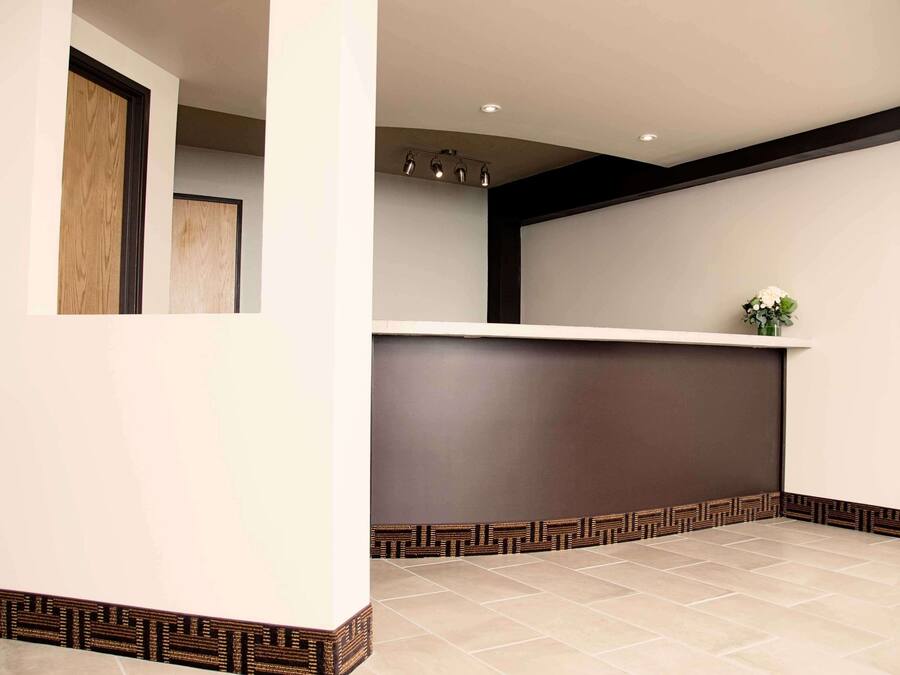 A reception area with a dark reception desk, a light-colored tiled floor, and a decorative border along the wall.