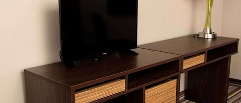 A dark wooden TV stand with a flat-screen TV and a lamp.