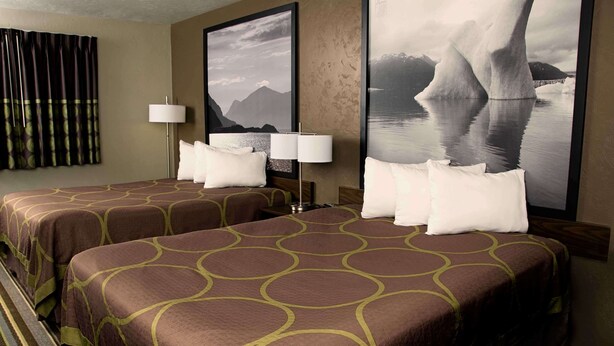 A hotel room with two beds, a large window with curtains, and two framed pictures on the wall. - Super 8 by Wyndham Juneau (Juneau)