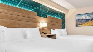 A hotel room with two beds, a wooden headboard, a nightstand with a lamp, and a painting of a mountain landscape. - Comfort Inn Fairbanks (Fairbanks)