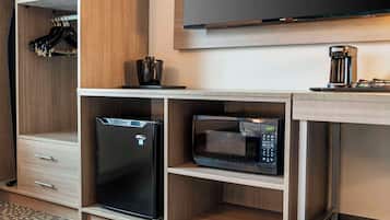 A compact kitchenette with a refrigerator, microwave, and coffee maker on a wooden countertop.