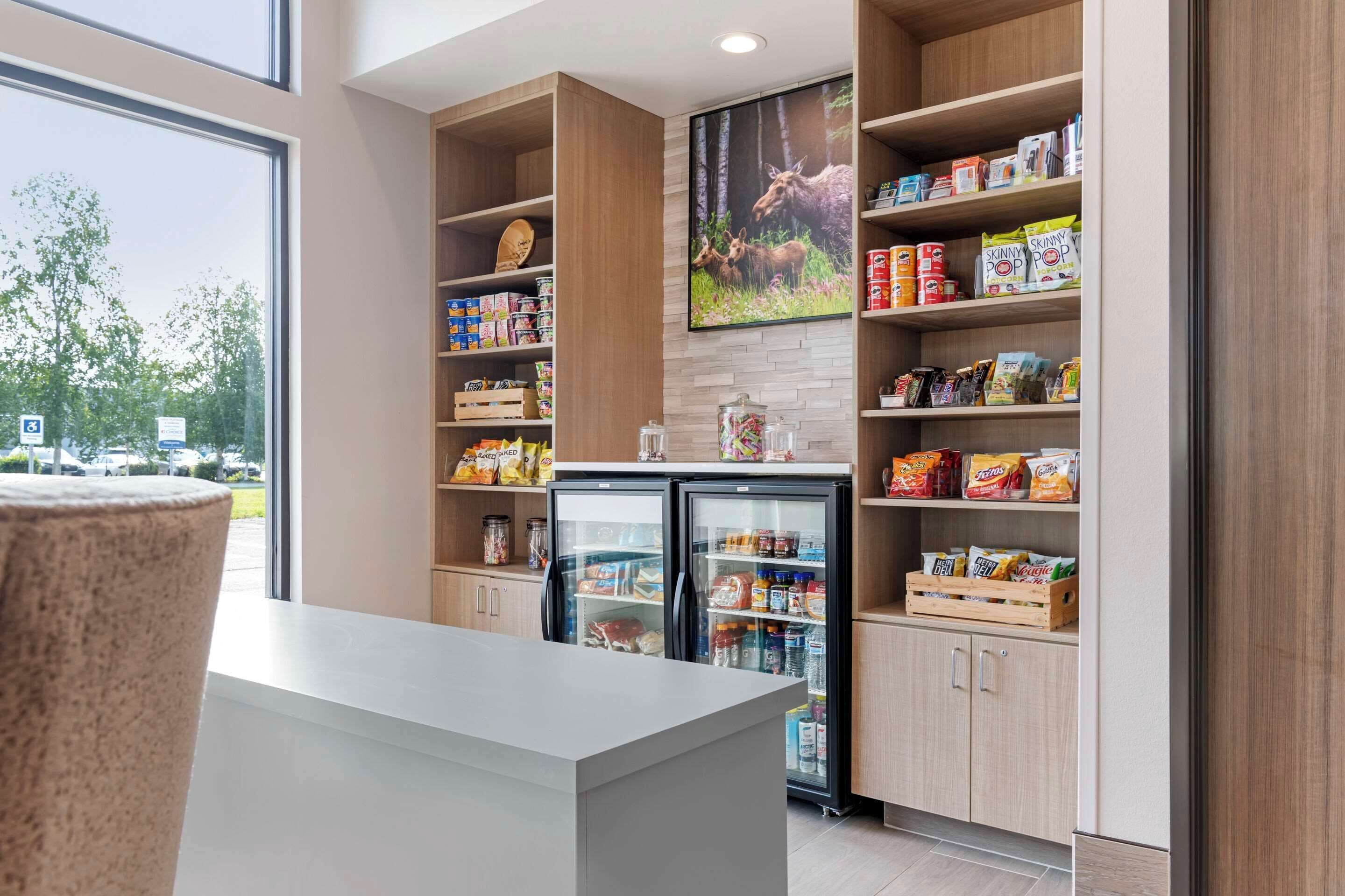 A modern kitchenette with wooden cabinetry, a built-in refrigerator, and a large window offering a view of the outdoors.