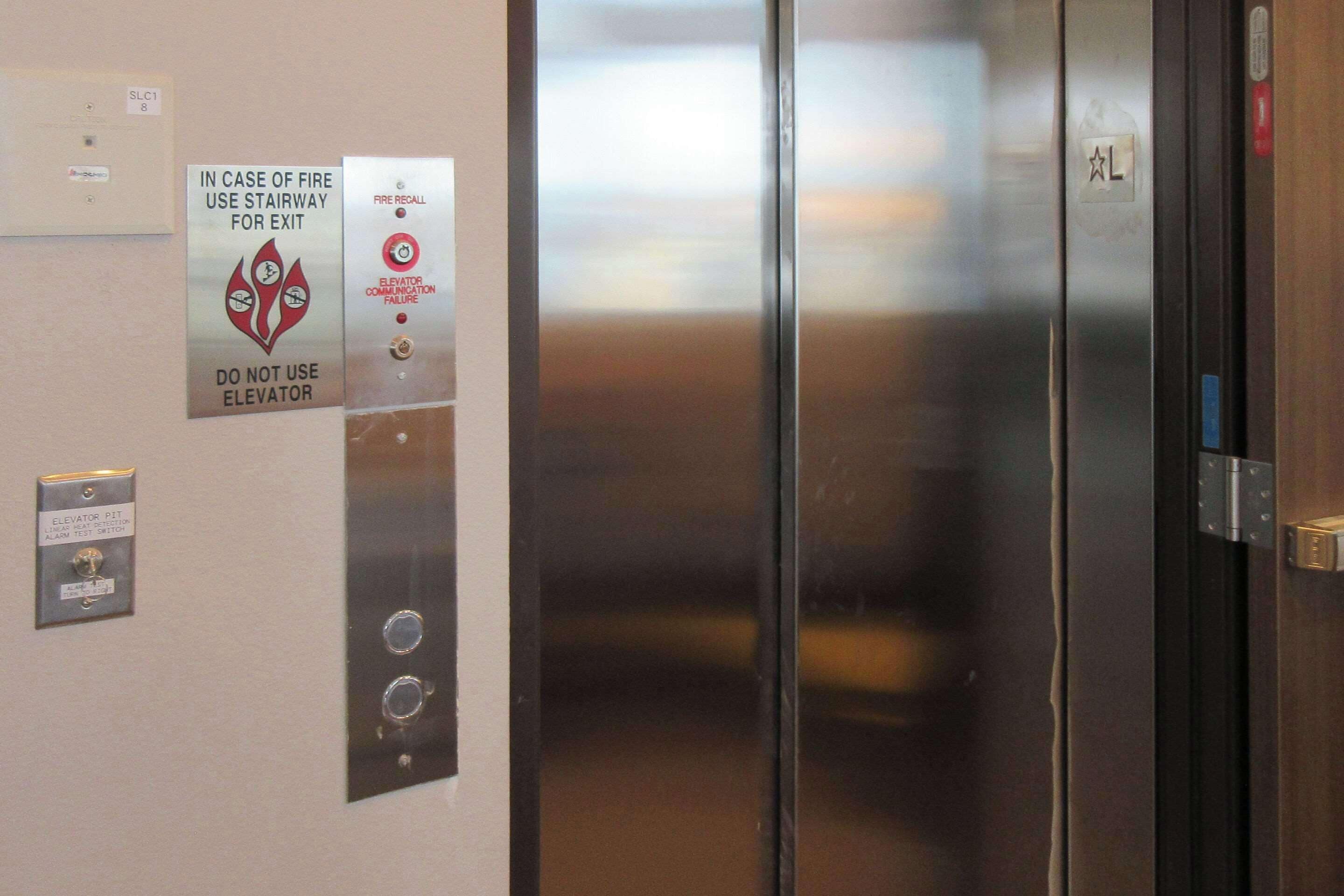An elevator with emergency instructions and a fire recall sign.