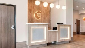 A reception area with a wooden wall, a crescent moon logo, and two reception desks with illuminated panels. - Comfort Inn Fairbanks (Fairbanks)