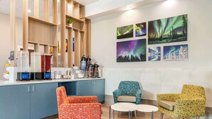 A modern hotel lobby with a wooden reception desk, a coffee station, and colorful chairs. - Comfort Inn Fairbanks (Fairbanks)