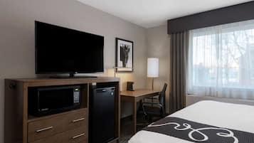 Une chambre d’hôtel équipée d’un lit, d’un bureau avec un ordinateur, d’un four à micro-ondes et d’une télévision.