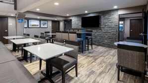 A modern restaurant with a stone wall, flat-screen TV, and multiple seating areas including booths and tables.