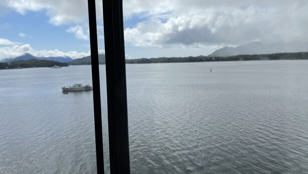 Ein ruhiger See mit einem Boot in der Ferne und Bergen im Hintergrund.