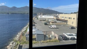 Ein Parkplatz mit Fahrzeugen, ein Gebäude mit der Aufschrift 'Alaska Marine Lines' und der Blick auf ein Gewässer mit Bergen im Hintergrund.
