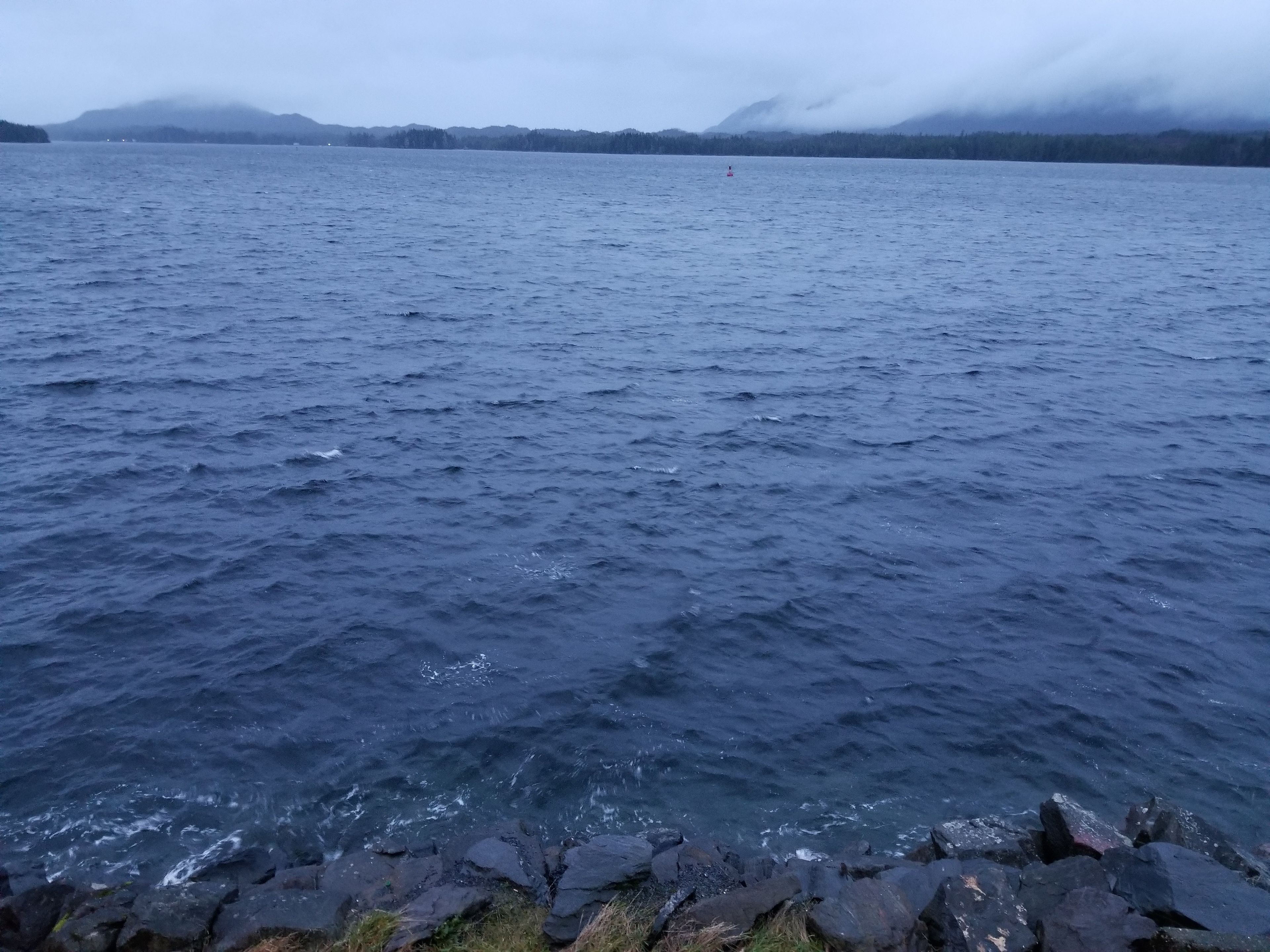 A calm body of water with a rocky shoreline in the foreground.