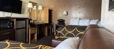 A hotel room with a bed, a desk with a computer, a microwave, and a television.